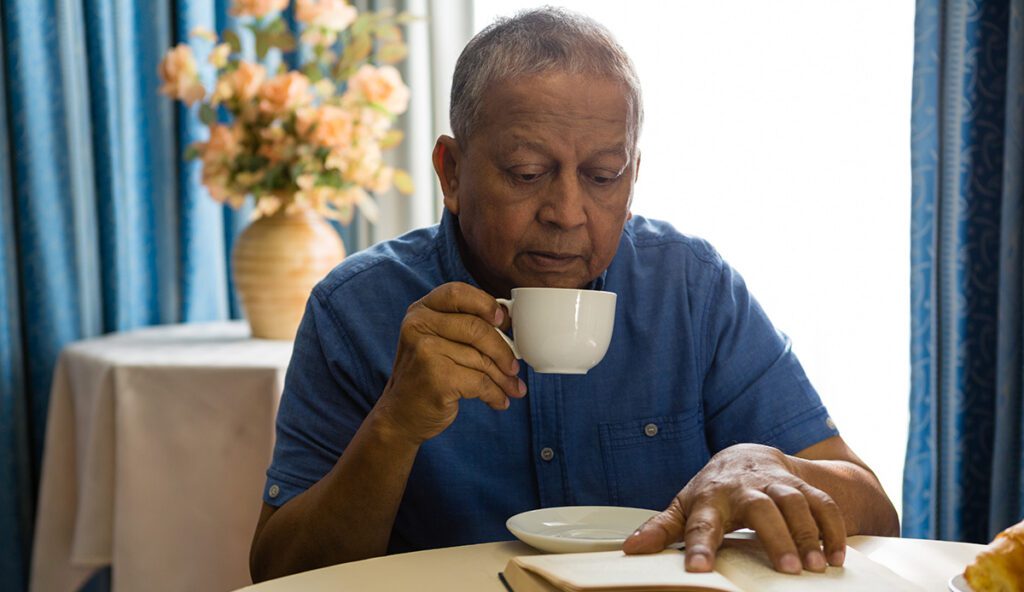 senior man reading a book with his coffee