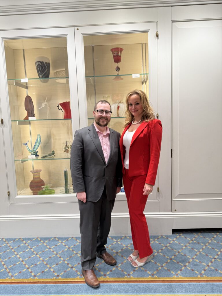 Rep. Adam Scanlon and Vitra Health CEO Lorena Silva standing side by side in front of a glass display case.